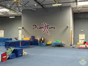 A large open gymnastics area with the Dream Xtreme logo on a wall