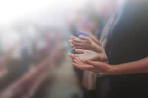 A hazy image of people raising hands to pray in church.