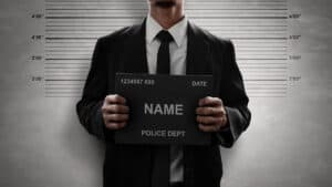 An unidentified man holds a name placard in a police station line-up area.